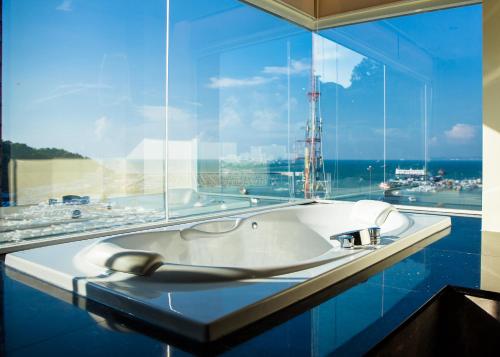 a bath tub in a room with a large window at Balihai Bay Pattaya in Pattaya South