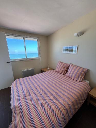 - une chambre avec un lit doté d'un couvre-lit rayé et 2 fenêtres dans l'établissement La Loggia, à Fort-Mahon-Plage
