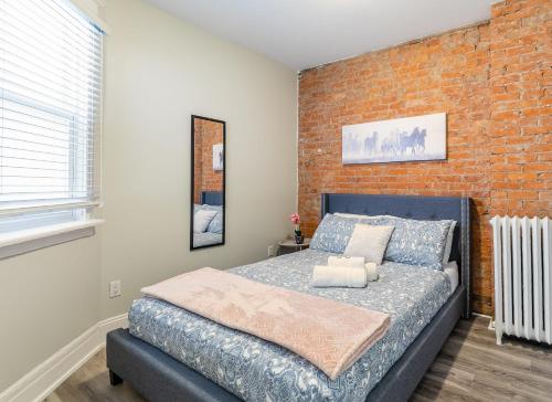a bedroom with a bed and a brick wall at 1BR - Queen Bed Apartment in Hamilton's Best Neighborhood in Hamilton