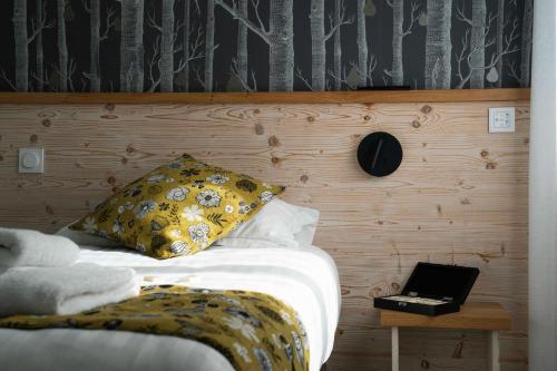 a bed with a pillow and a table with a laptop at Logis Hôtels Gnàc é Pause in Saint-Lon-les-Mines