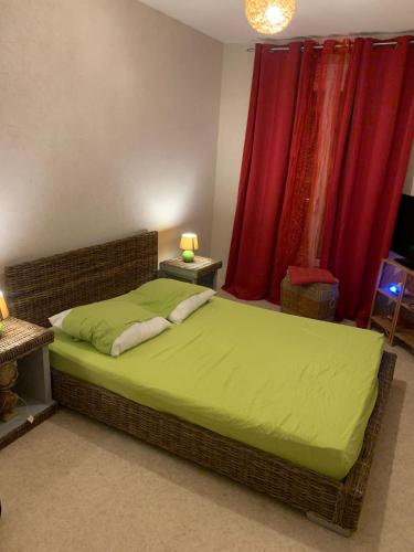 une chambre avec un lit avec des draps verts et des rideaux rouges dans l'établissement Le Moulin de la Mer, Grand appartement en face de la Piscine du Parc des sports, à Perpignan