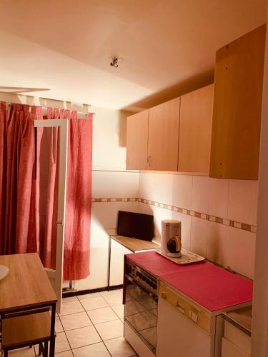 - une cuisine avec un comptoir rouge dans une pièce dans l'établissement Le Moulin de la Mer, Grand appartement en face de la Piscine du Parc des sports, à Perpignan