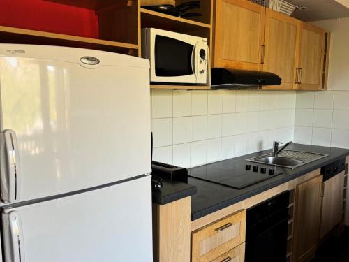 La cuisine est équipée d'un réfrigérateur blanc et d'un four micro-ondes. dans l'établissement Résidence Le Centaure - 3 Pièces pour 6 Personnes 661, à Aime La Plagne