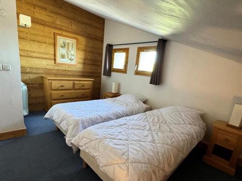 - 2 lits dans une chambre dotée de murs en bois dans l'établissement Résidence Le Centaure - 2 Pièces pour 4 Personnes 701, à Aime La Plagne