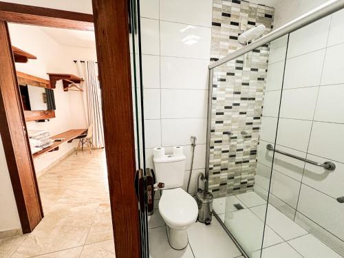 a bathroom with a toilet and a glass shower at Conchas do Mar Residence in Itacaré