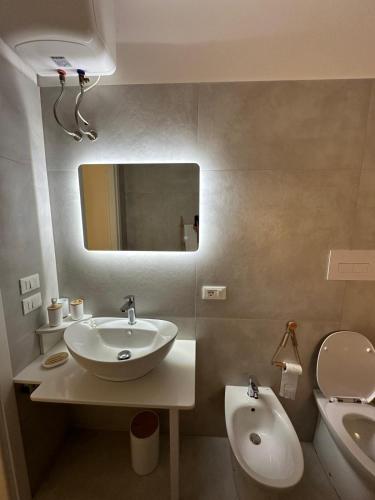 a bathroom with a sink and a toilet and a mirror at Summertime's House in Peschici