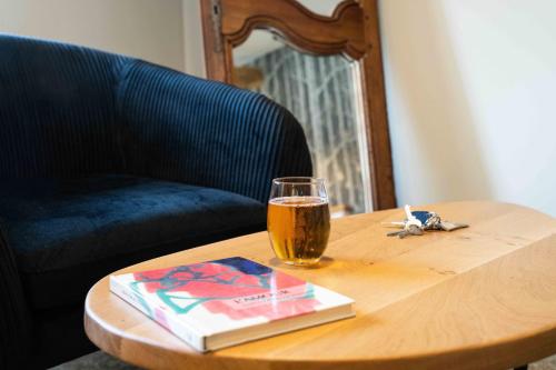 a glass of beer and a book on a wooden table at Logis Hôtels Gnàc é Pause in Saint-Lon-les-Mines