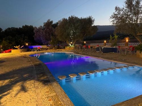 a swimming pool with blue water and stools around it at Auberge Alwahabi in Chefchaouene