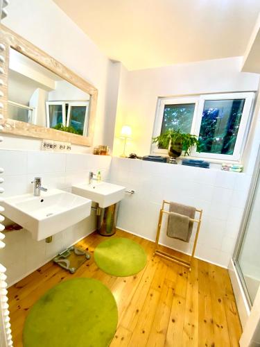 La salle de bains est pourvue de 2 lavabos et d'un tapis vert. dans l'établissement LA VILLA DES OISEAUX - La Petite Pierre, à La Petite-Pierre