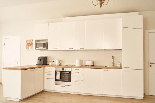 a white kitchen with white cabinets and appliances at Beachfront apartment in Jūrmala
