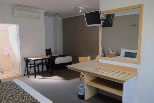 a hotel room with a bed and a desk with a mirror at Berri Hotel in Berri