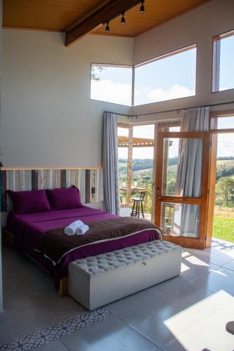 a bedroom with a purple bed and a large window at Cabana com jacuzzi e churrasqueira - Ibiuna SP in Bairro Murundu