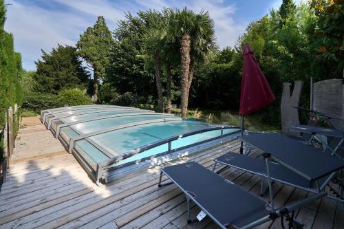a swimming pool with two tables and an umbrella at Gite STANDING climatisé avec piscine chauffée et SPA PRIVATIF in Alzonne