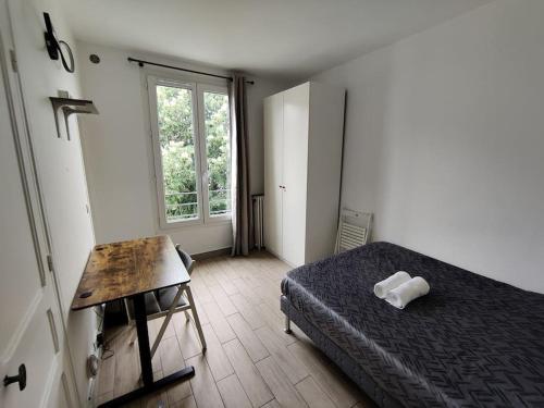 une chambre avec un lit, un bureau et une fenêtre dans l'établissement Studio Tour Eiffel, à Aulnay-sous-Bois