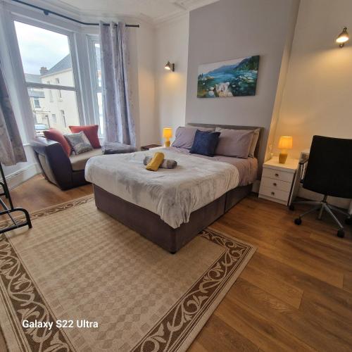 a bedroom with a large bed and a living room at 5 Bed Plymouth Home-Free Parking - Close to City Centre in Plymouth