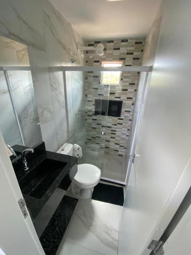 a white bathroom with a toilet and a sink at Flat no Cond Home Duplex - Subida da Serra in Bezerros