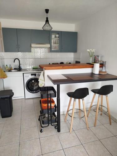 une cuisine avec une table et trois tabourets de bar dans l'établissement L'appartement de Juju, à Bayonne