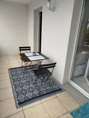une table et deux chaises sur un tapis sur une terrasse dans l'établissement L'appartement de Juju, à Bayonne