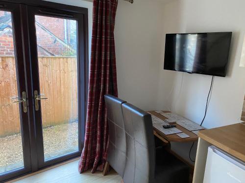 a room with a desk with a television and a table with a deskngthngth at Clock Tower Cottage in Nailsworth
