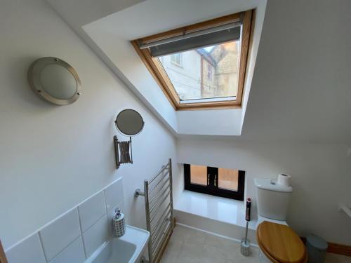 a bathroom with a toilet and a skylight at Clock Tower Cottage in Nailsworth