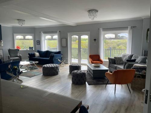 a living room with couches and chairs and windows at Greenane House in Killarney