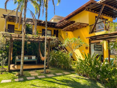 a yellow house with a hammock in the yard at Conchas do Mar Residence in Itacaré