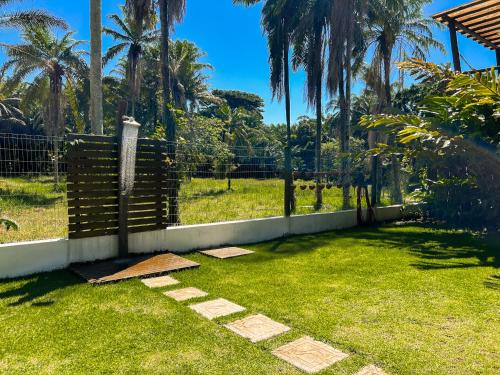 a backyard with a fence and grass and palm trees at Conchas do Mar Residence in Itacaré