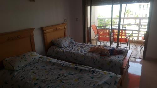 two beds in a bedroom with a view of a patio at superbe appartement vue piscine in Bouznika
