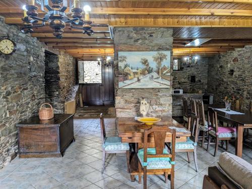 a dining room with a stone wall and a table and chairs at O Val de Vilaboa in Bóveda