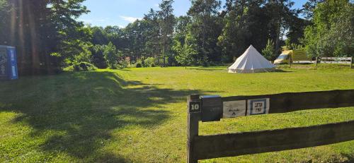 a field with a tent in the background and a fence at Mietwohnwagen in Carpin