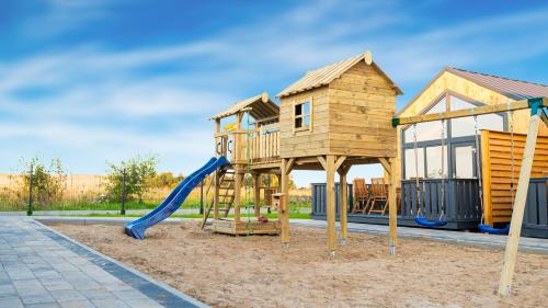 a wooden playground with a slide and a house at Nadmorskie Chatki - SAUNA - OPCJA Z PRYWATNĄ BALIĄ KĄPIELOWĄ LUB BEZ in Gąski