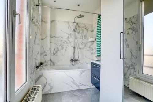 a white bathroom with a tub and a shower at Superbe T3 très proche Gare Sartrouville in Sartrouville