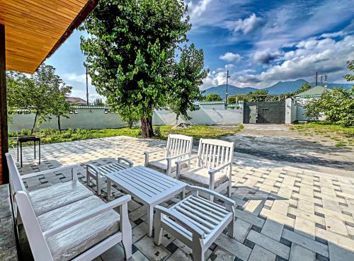 eine Gruppe weißer Bänke auf einer Terrasse in der Unterkunft Qafqaz Resort Greenway in Qəbələ