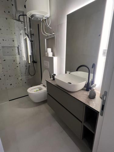 une salle de bains avec lavabo, toilettes et douche dans l'établissement Sunny apartments, à Ulcinj