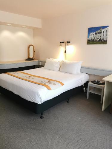 a hotel room with a large bed with white sheets at The Angus Hotel in Lower Hutt