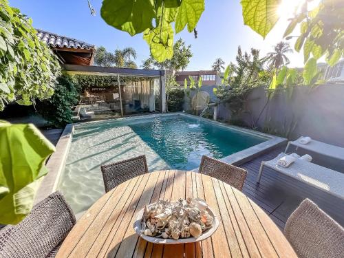 a table and chairs in front of a swimming pool at Casa com piscina aquecida, cozinheira, 30m do mar in Barra do Camaragibe