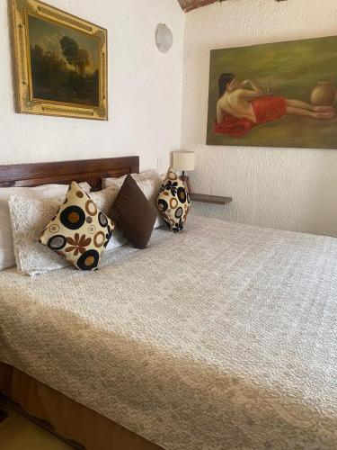 a bedroom with a bed with pillows and a painting at Hotel Villas Ajijic, Ajijic Chapala Jalisco in Ajijic