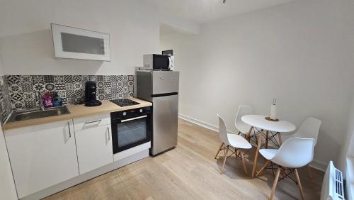 Il comprend une cuisine équipée d'une cuisinière et d'une table avec des chaises blanches. dans l'établissement L'Urbain IV - Hypercentre Troyes, place mairie, à Troyes