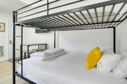 Kimberling CityにあるCharming Studio with Pool and Table Rock Lake Access!の白いシーツと黄色い枕が置かれた二段ベッド
