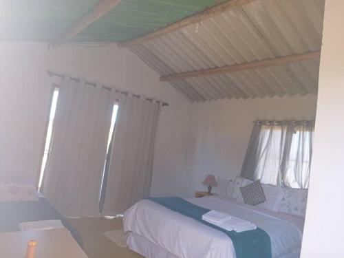 a white bedroom with a bed and two windows at chalé jasmim in Alto Paraíso de Goiás