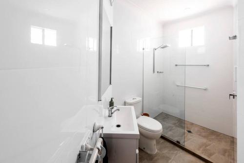 a white bathroom with a toilet and a shower at Ludere Normanville in Normanville
