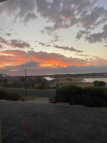a sunset with a cloudy sky and a brick road at Ludere Normanville in Normanville