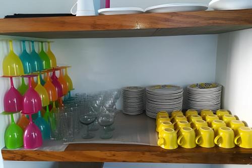 a shelf with colorful bottles and glasses and plates at Descanso total en el mejor clima de Colombia in Anapoima