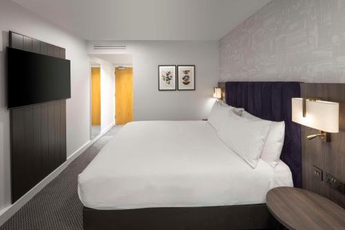 a hotel room with a large bed and a tv at DoubleTree by Hilton Manchester Piccadilly in Manchester