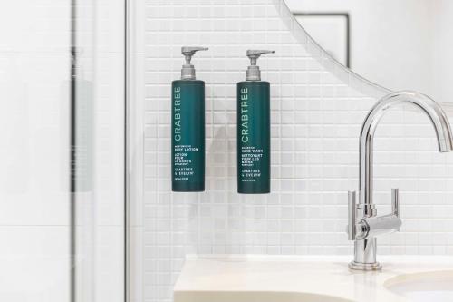two bottles ofodorizers are on the wall of a bathroom at DoubleTree by Hilton Manchester Piccadilly in Manchester