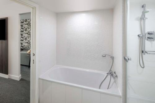 a white bathroom with a tub and a shower at DoubleTree by Hilton Manchester Piccadilly in Manchester