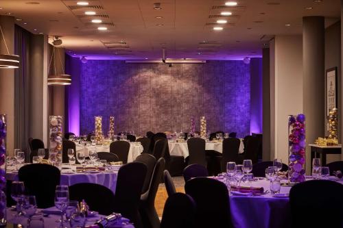 a conference room with tables and chairs with purple lighting at DoubleTree by Hilton Manchester Piccadilly in Manchester