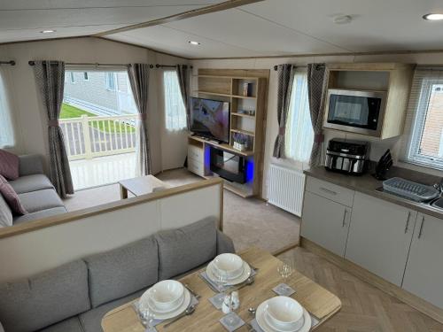 a living room with a couch and a table at Golden Palm Resort - The Blenheim Retreat - Coastal Caravan Breaks in Chapel Saint Leonards