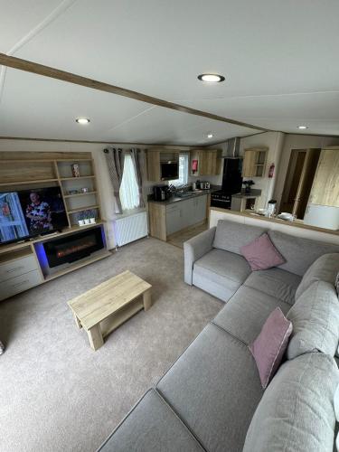 a living room with a couch and a table at Golden Palm Resort - The Blenheim Retreat - Coastal Caravan Breaks in Chapel Saint Leonards