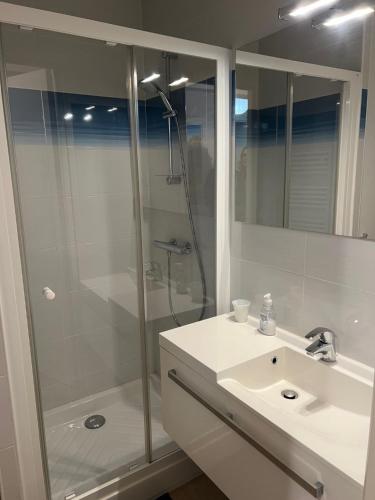une salle de bain blanche avec une douche et un lavabo dans l'établissement L'Eau Vive 2 Front de mer 2e étage, à Le Touquet-Paris-Plage
